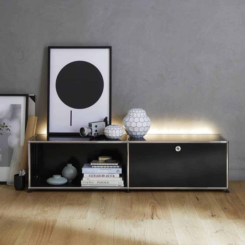 Ein niedriges, hinterleuchtetes Sideboard mit einer geschlossenen Klappe und einer offenen &Ouml;ffnung